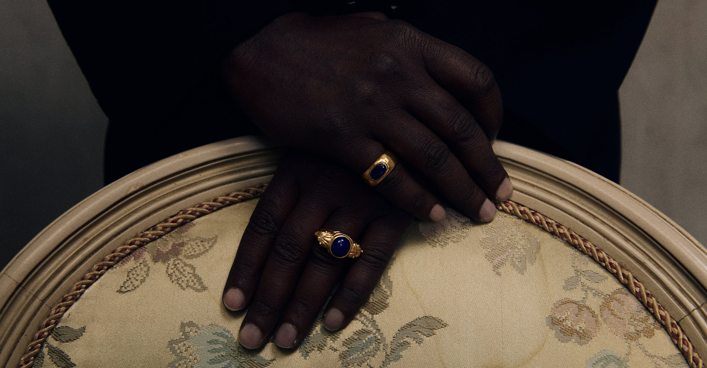 Cleopatra’s Bling: hands resting on an armchair, wearing gold and lapis lazuli rings